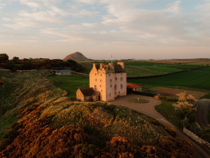 Aerial view of Fenton Tower wedding venue set within rolling East Lothian countryside at golden hour
